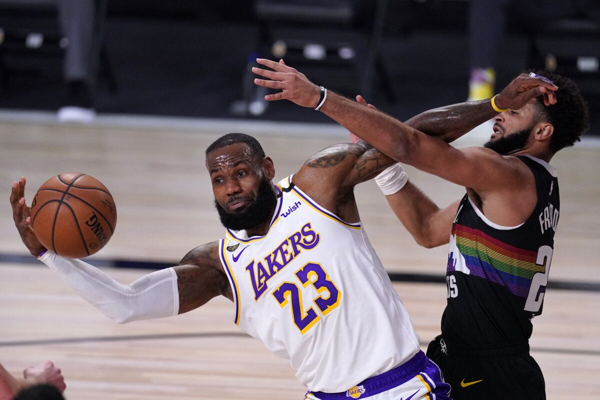 Lakers forward LeBron James, left, tries to maintain control of the ball in front of Denver Nuggets guard Jamal Murray.
