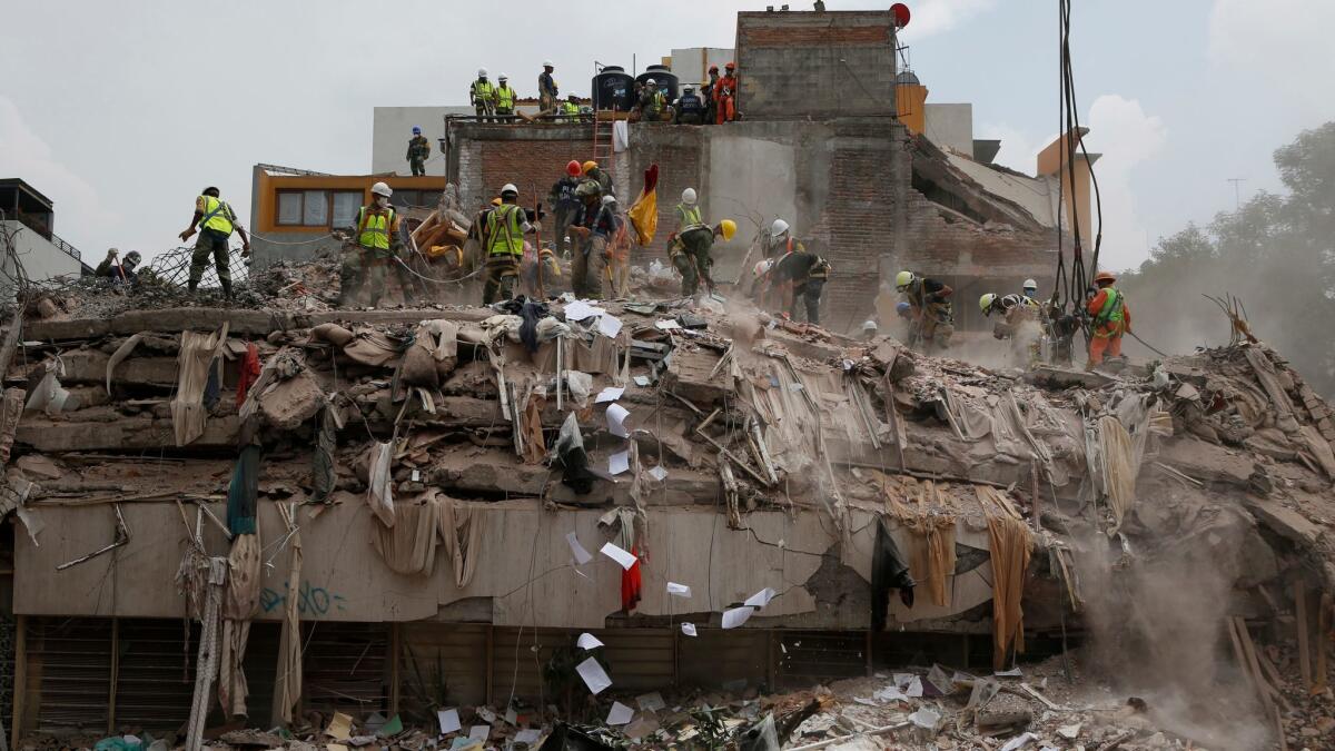 Workers shovel papers and debris off the top of the rubble of a building that collapsed in last week's Mexico earthquake, in the Del Valle neighborhood of Mexico City.