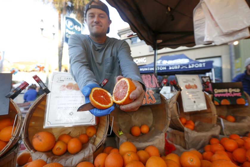 Mike Rosendahl shows a cara cara orange during the spring grand opening and celebration of Surf City Nights, the Huntington Beach farmer's market and street fair, on Tuesday. The Surf City Night opening was also HBPD appreciation night.