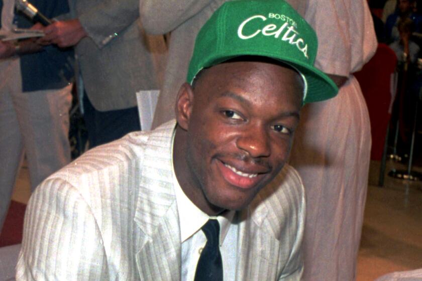 A man in a suit wearing a Boston Celtics cap