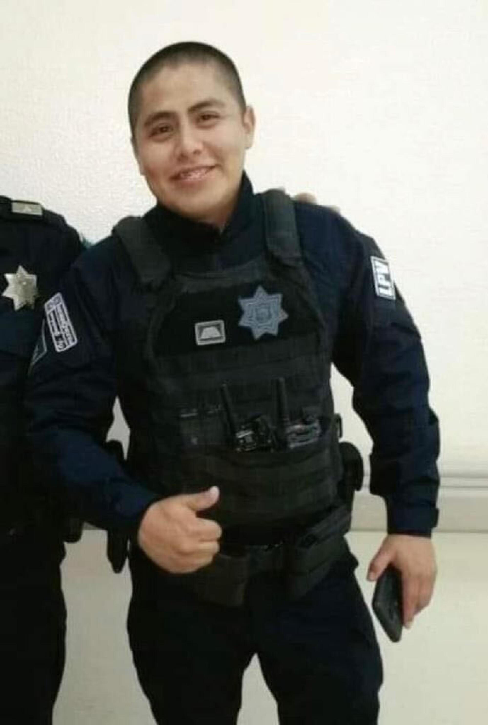 A young man in a police uniform gives a thumbs-up.