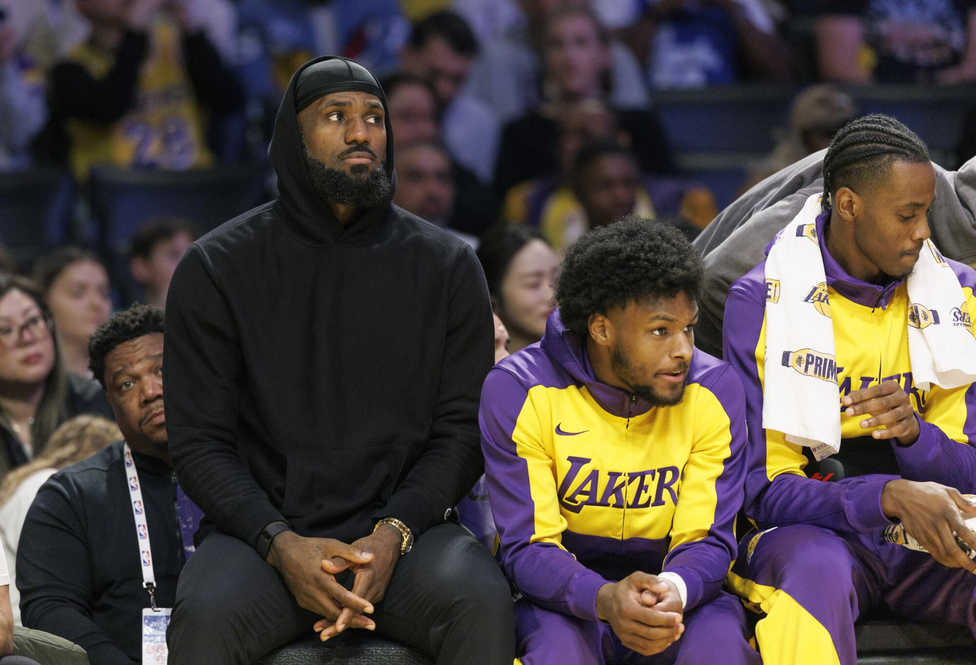 LeBron James sits on the bench next to Bronny James.
