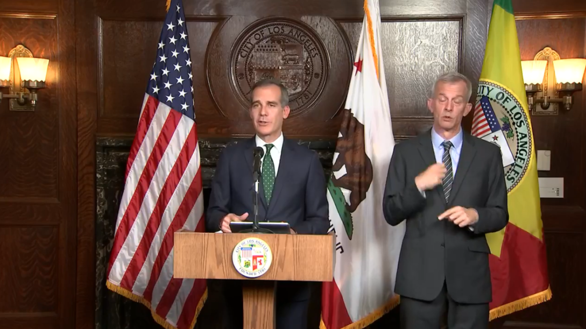 Mayor Eric Garcetti speaks at a lectern in front of U.S., California and Los Angeles flags