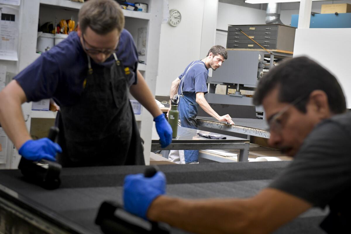 Three men making art prints in a workshop.