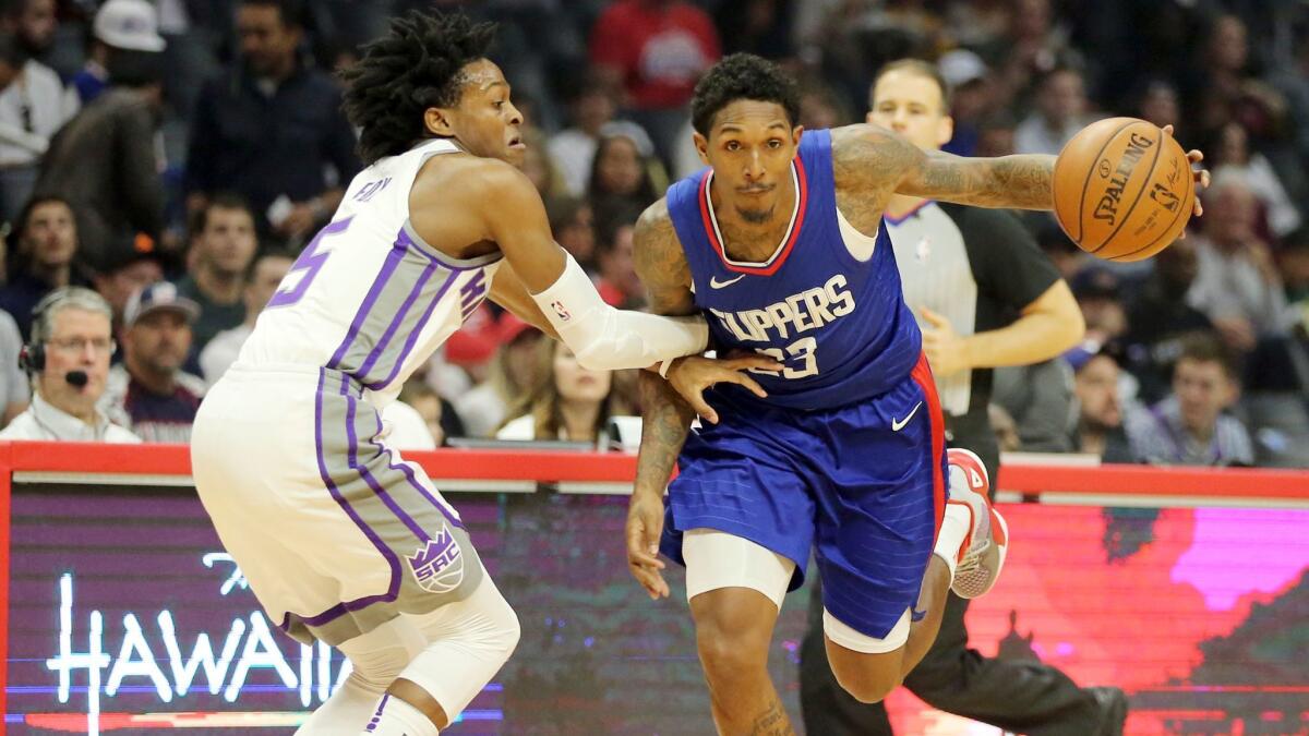 Sacramento Kings guard De'Aaron Fox defends as Clippers guard Lou Williams drives in the first quarter.