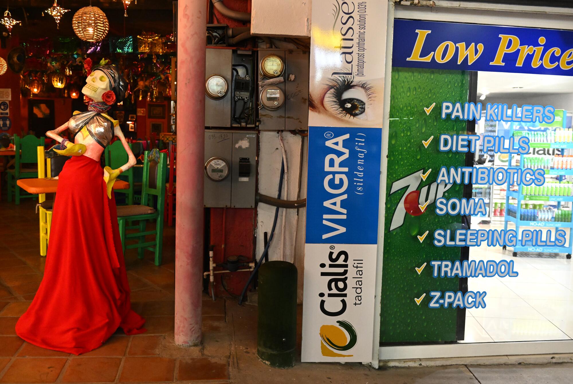 Colorful decor including a skeleton in a red skirt next to a store advertising medications including painkillers in English
