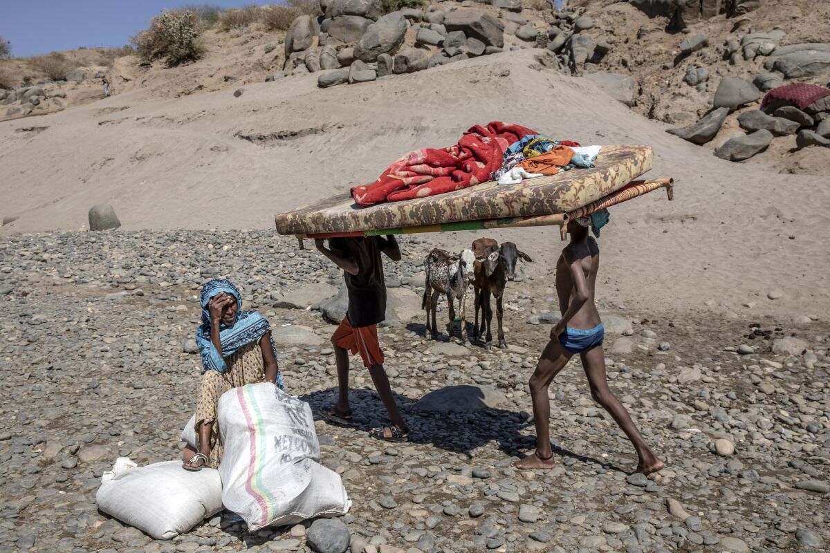 Refugees carry their belongings in eastern Sudan including a mattress and blankets.