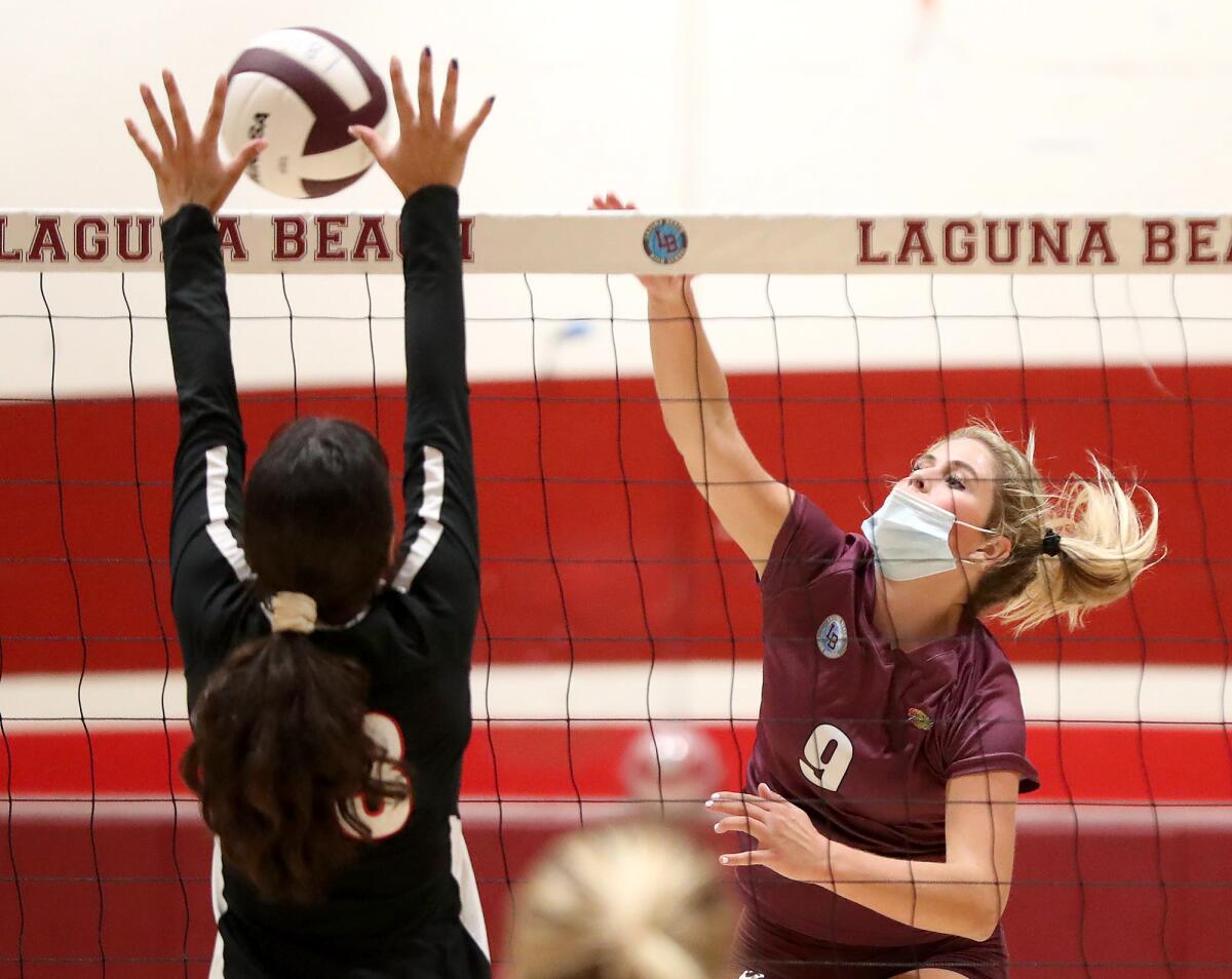 Laguna Beach's Brooklyn Yelland (9) goes up against La Cañada  Flintridge Sacred Heart blocker Milena Andrade for a kill.