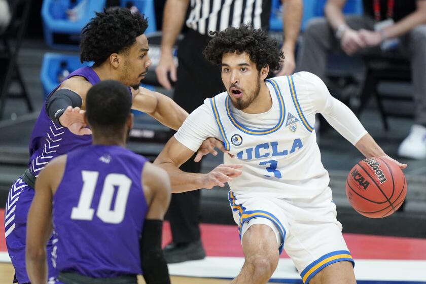 UCLA's Johnny Juzang (3) is defended by Abilene Christian's Coryon Mason, left, and Reggie Miller (10) during the first half of a college basketball game in the second round of the NCAA tournament at Bankers Life Fieldhouse in Indianapolis Monday, March 22, 2021. (AP Photo/Mark Humphrey)