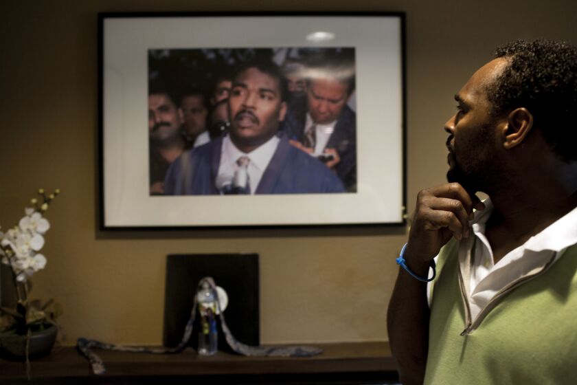 Rodney King looks at a picture of himself from May 1, 1992, the third day of the Los Angeles riots, which hangs in the living room of his home in Rialto, in 2012. At that press conference, King uttered the famous words, "Can we all get along?"
