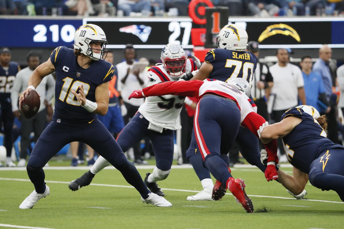 The Patriots put  pressure on Chargers quarterback Justin Herbert (10).