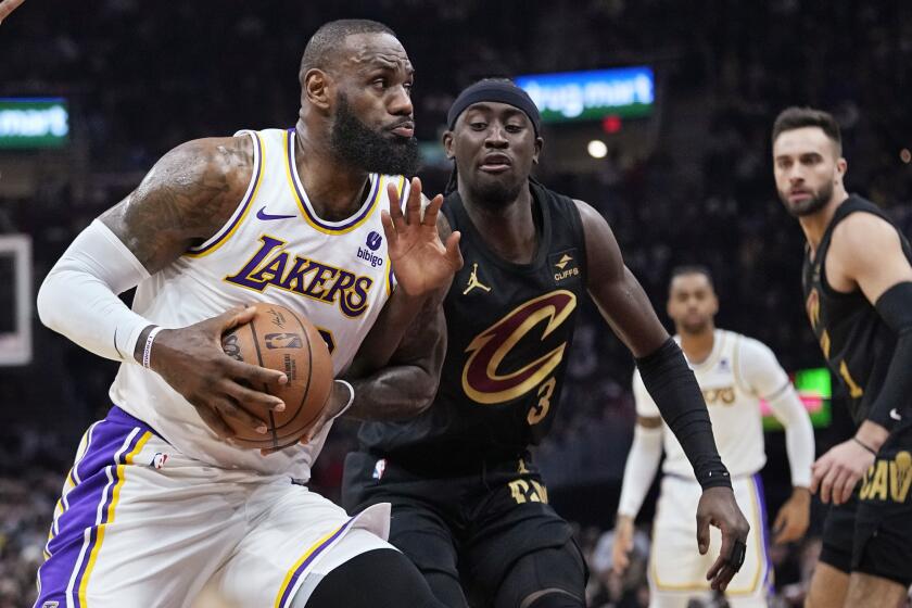 Los Angeles Lakers forward LeBron James, left, is fouled by Cleveland Cavaliers guard Caris LeVert as he drives to the basket during the first half of an NBA basketball game Saturday, Nov. 25, 2023, in Cleveland. (AP Photo/Sue Ogrocki)