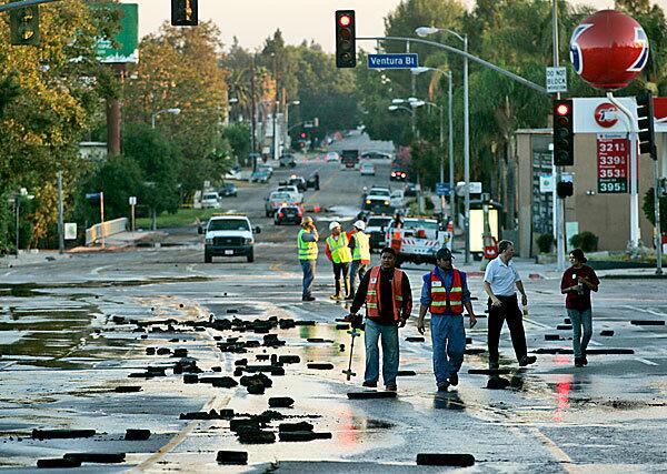 Coldwater Canyon Avenue is littered with broken pieces of pavement after a water main break overnight flooded the Studio City neighborhood and created a large sinkhole under the street, which then collapsed.
