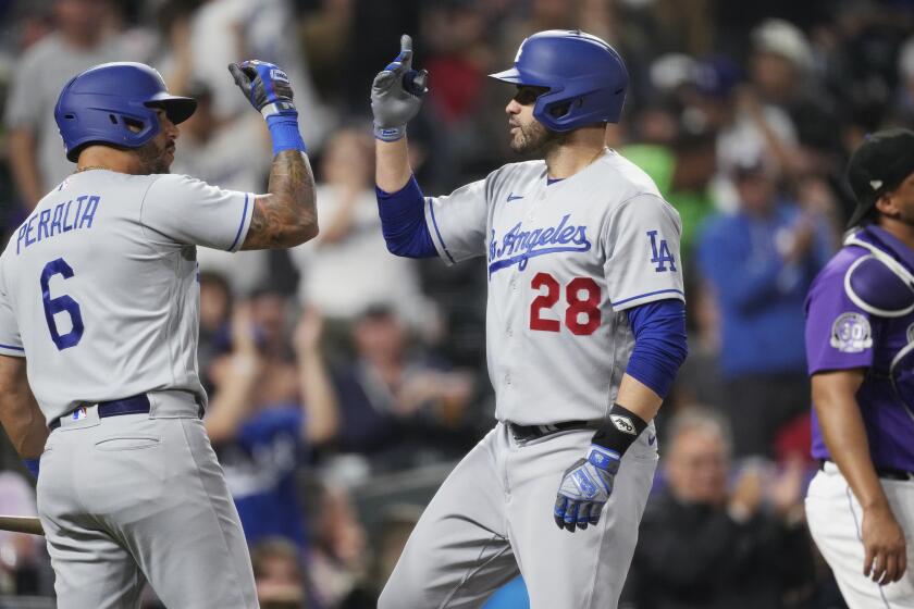 Los Angeles Dodgers' David Peralta, left, congratulates J.D. Martinez after his two-run home run off Colorado Rockies relief pitcher Peter Lambert during the fourth inning of a baseball game Thursday, June 29, 2023, in Denver. (AP Photo/David Zalubowski)