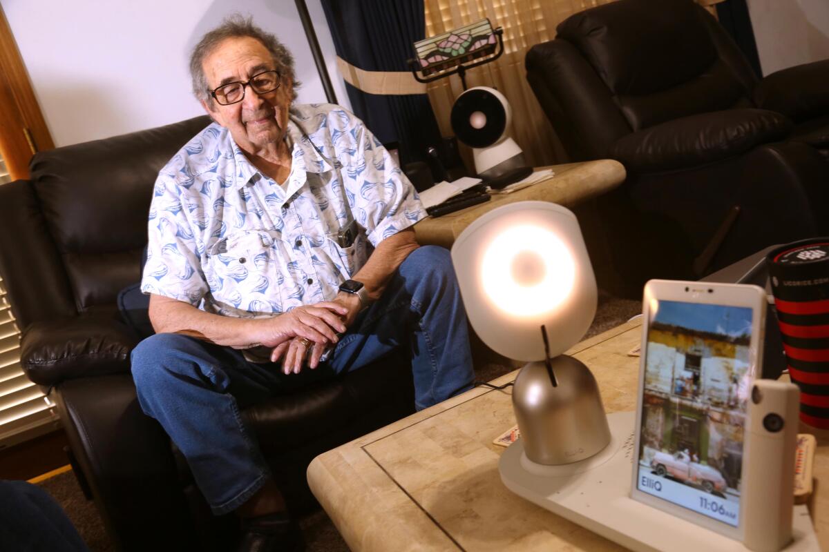 Ken Mattlin, 86, asks a question of a robot resembling a table lamp at his home in Bakersfield. 