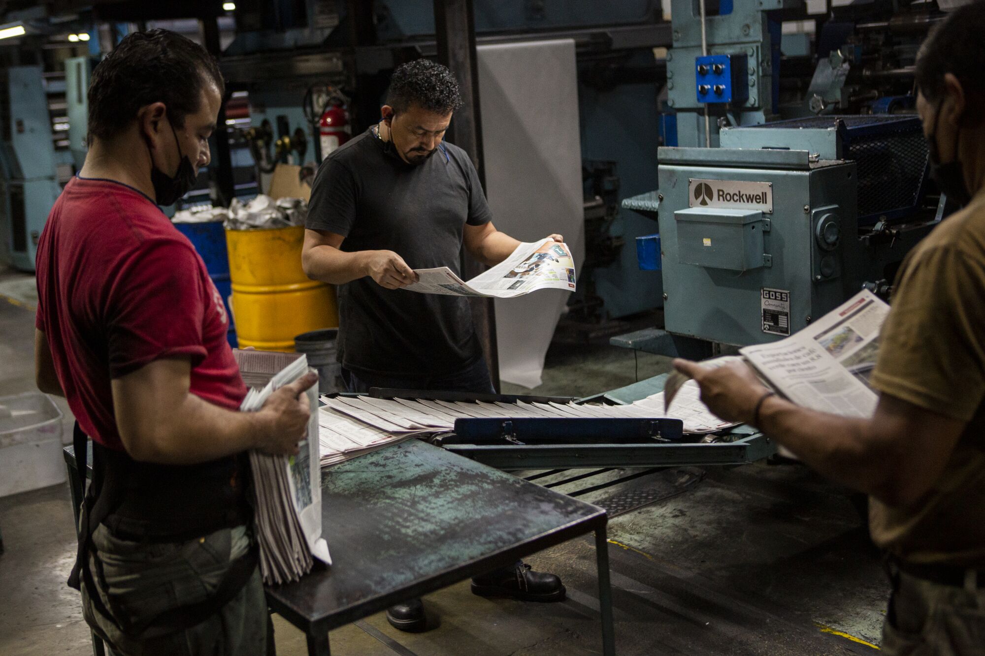 Workers at the el Periodico newspaper's printing press review last details before they are packed for distribution