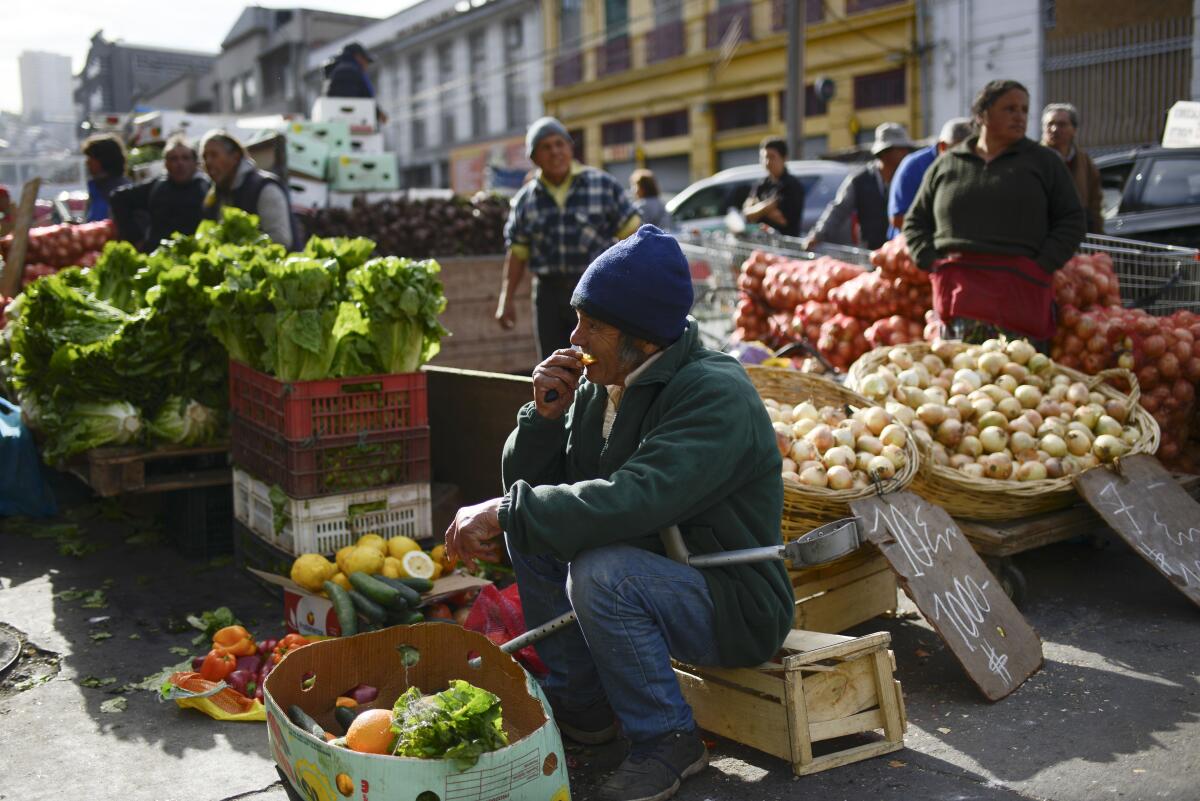 A man offers his vegetables in a market in Valparaiso, Chile, Friday, Oct. 25, 2019. At least 18 people have died in a week of nationwide clashes and looting sparked by a hike in subway fares. (AP Photo/Matias Delacroix)