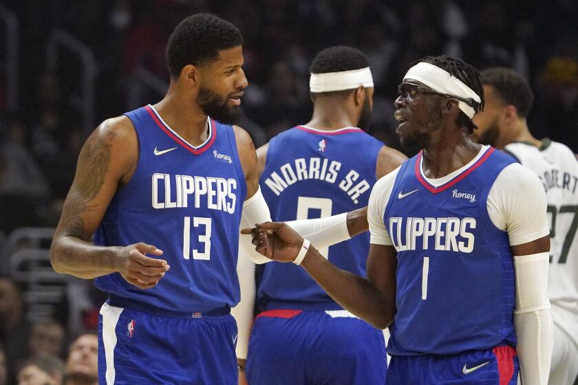 Los Angeles Clippers guard Paul George, left, and guard Reggie Jackson talk during the first half of an NBA basketball game against the Utah Jazz Tuesday, March 29, 2022, in Los Angeles. (AP Photo/Mark J. Terrill)
