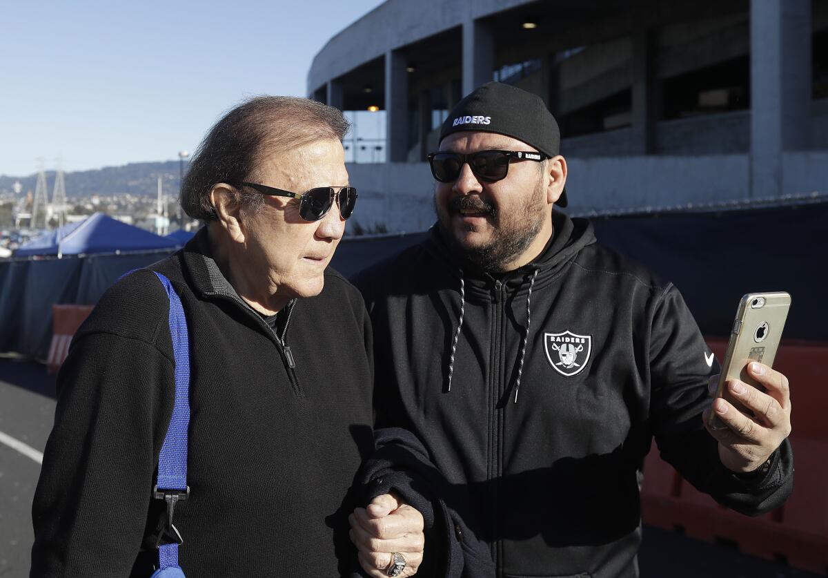 Former Oakland Raiders head coach Tom Flores takes a photo with a fan.