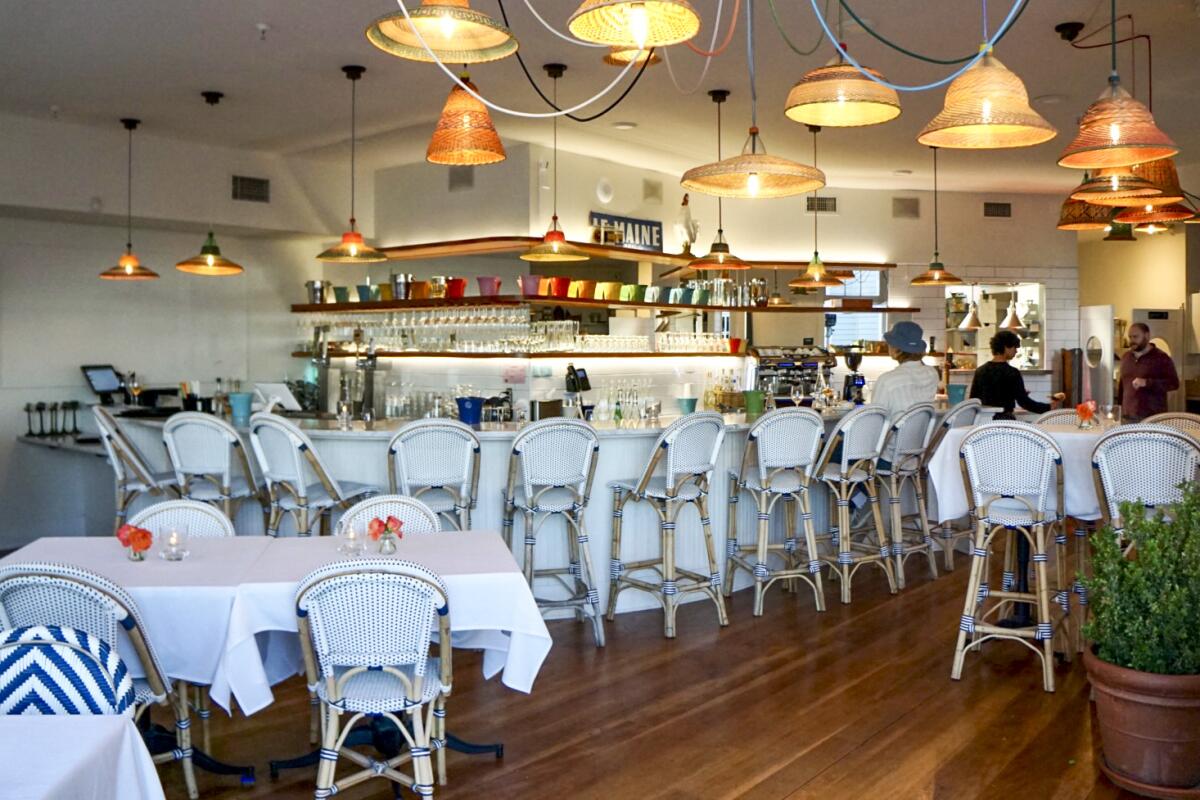 The interior of Blue Moon Over Avila features white rattan chairs and a bar.