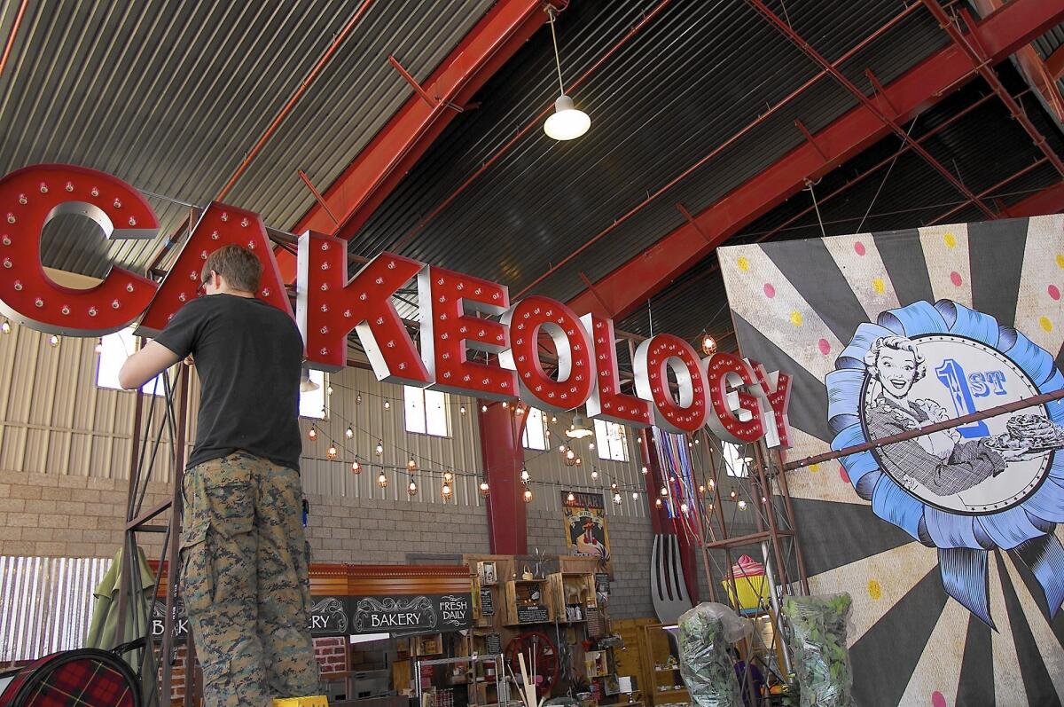 Nolan Dexter-Brown works on a sign for Cakeology in preparation for the opening of the OC Fair on Thursday.