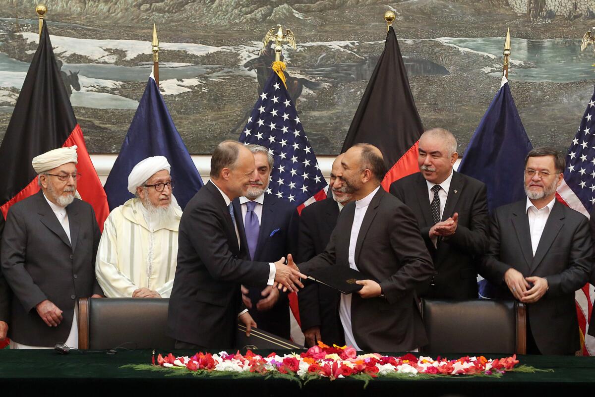 Afghanistan's national security advisor, Mohammad Hanif Atmar, third from right, and U.S. Ambassador James Cunningham shake hands Sept. 30 after signing a security agreement that will allow American troops to remain in Afghanistan.
