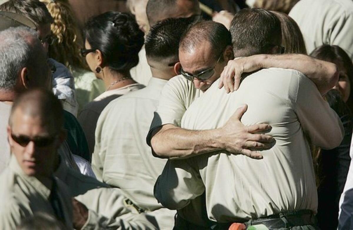 Two U.S. Forest Service firefighters embrace after the funeral for Capt. Mark Loutzenhiser at Idyllwild School in Idyllwild.