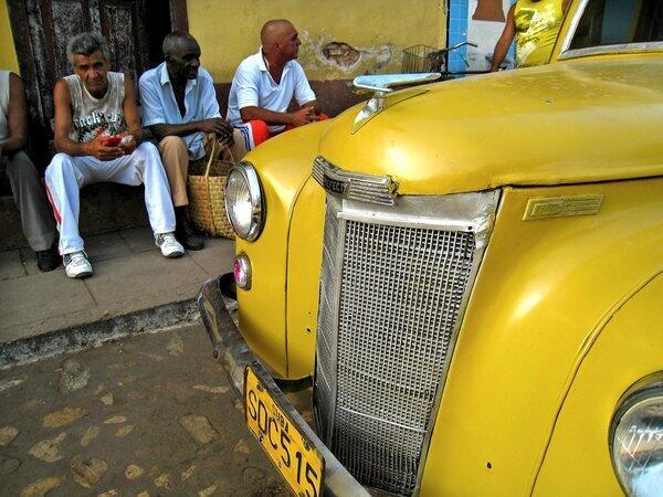 Local men sit by a colorful old roadster.