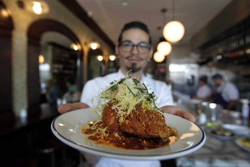 Chef de Cuisine Sydney C. Hunter III displays the chicken leg, which is strewn with bread crumbs, crisped in brown butter and topped with a handful of frisee salad.