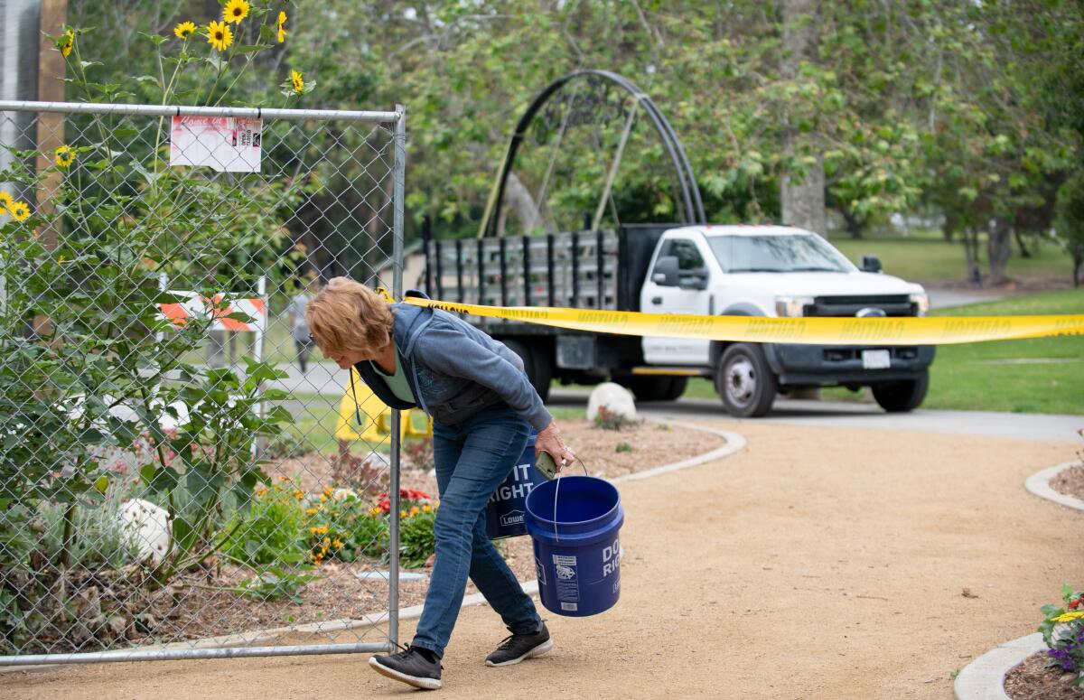 Shari Engel ducks under caution tape as a new archway for the Secret Garden arrives at Huntington Central Park Friday.