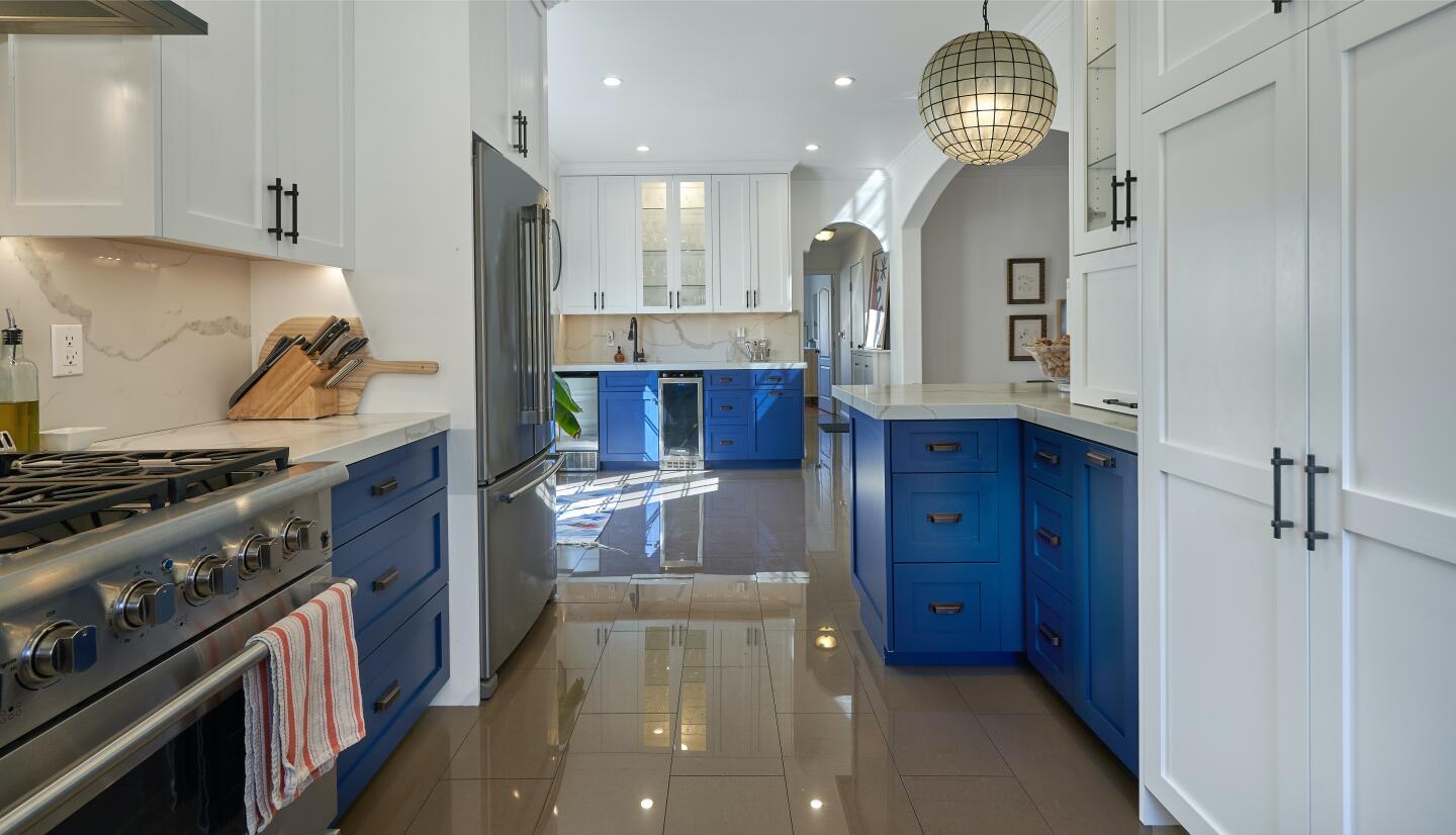 The kitchen with appliances and blue and white cabinets.