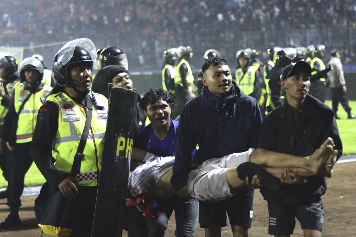 Soccer fans carry an injured man inside a soccer stadium