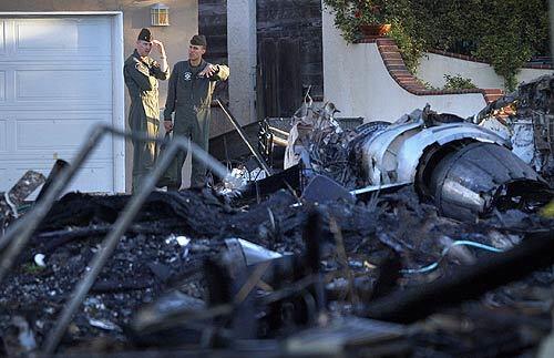 Military investigators view the wreckage of an F/A-18D Hornet jet that crashed into a home in San Diego's University City neighborhood, west of Marine Corps Air Station Miramar. Three people were killed and a fourth person remained missing in Monday's crash. The pilot, a Marine on a training mission, ejected safely.