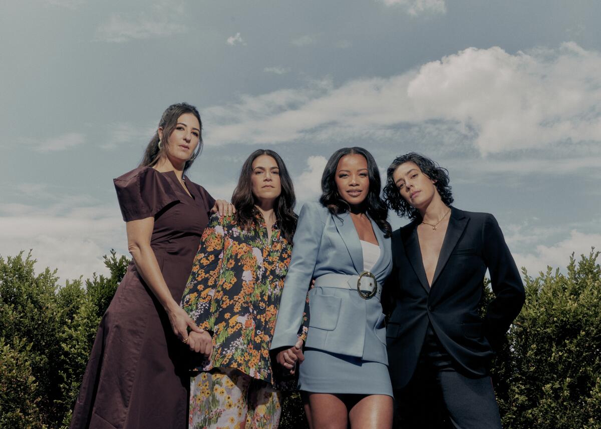  Four women stand together linking hands