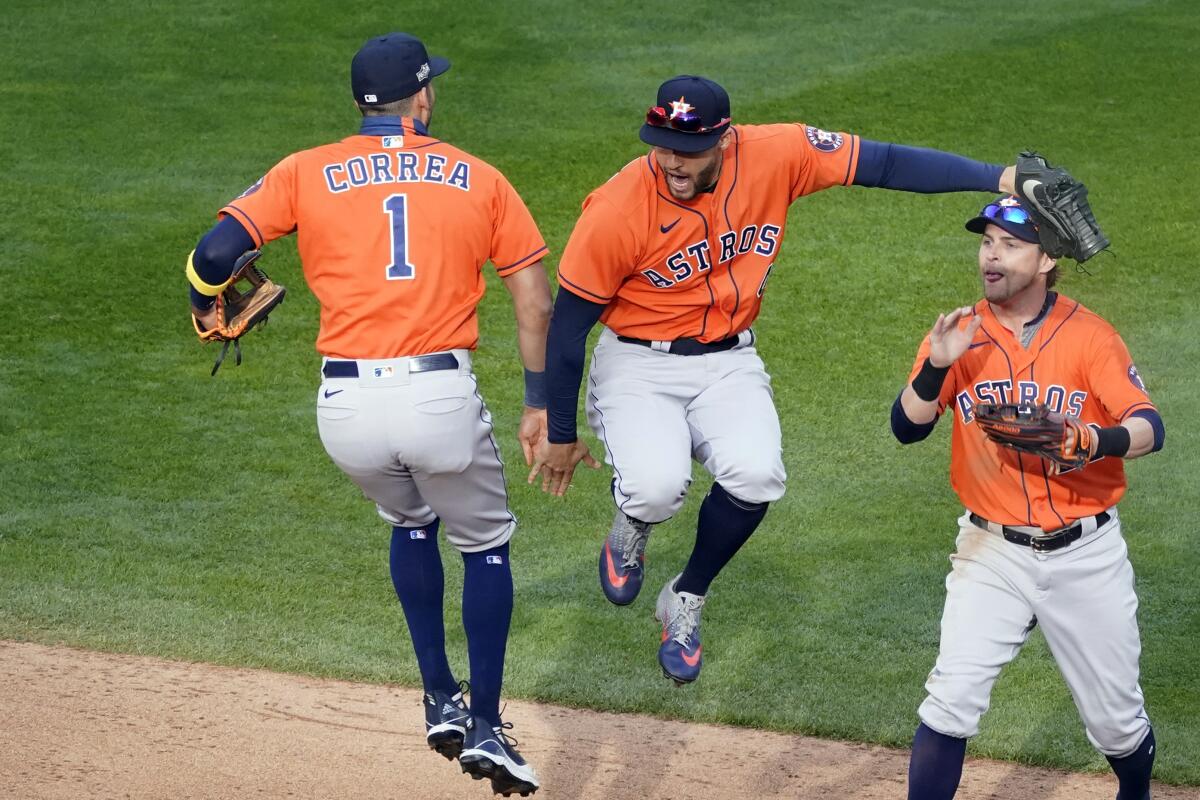 Houston's Carlos Correa, left, and George Springer jump in celebration next to Josh Reddick