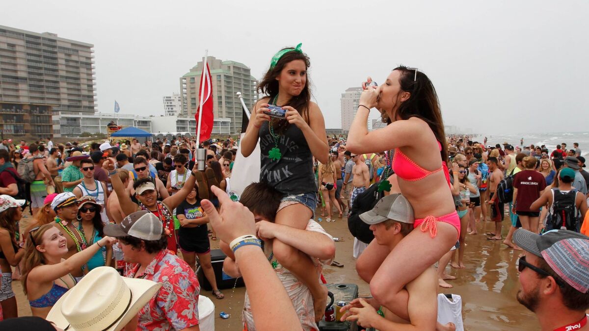 Students drink beer while celebrating spring break on the beach on March 17, 2016, at South Padre Island, Texas.