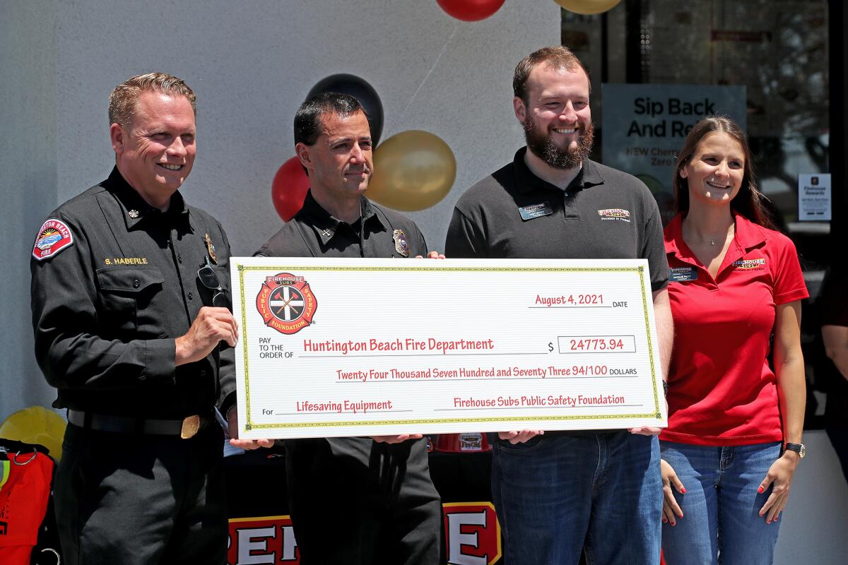 Fire Chief Scott Haberle and Justin Fleming accept a grant from Firehouse Subs owners Troy Ruoff and Natalie Fritz.