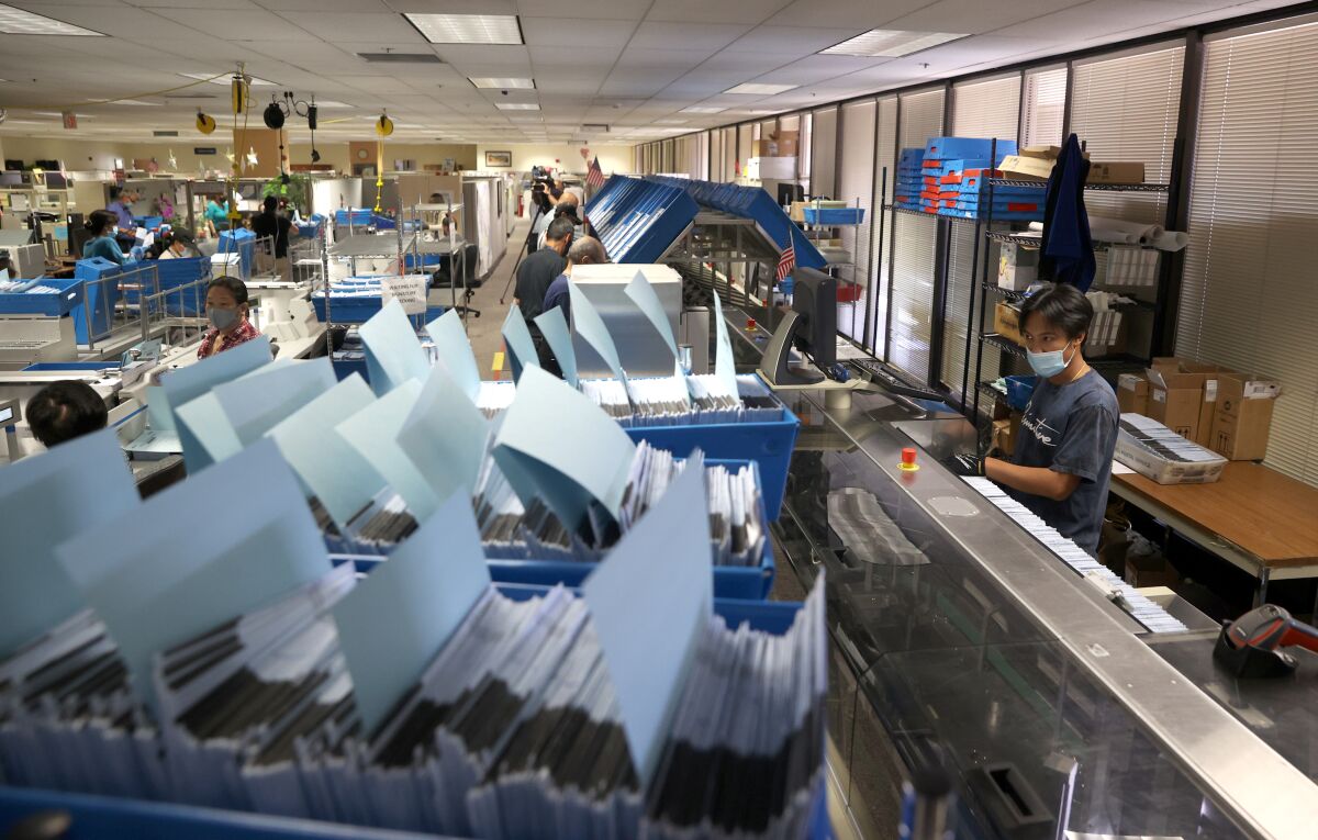 A worker runs mail-in-ballots through a sorting machine 