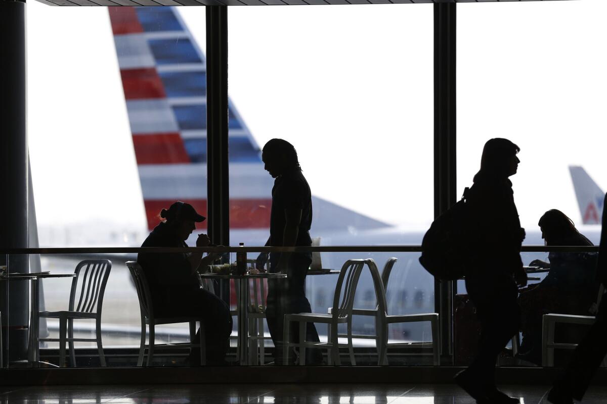 Travelers sit and eat while an American Airlines plane, with its new logo on the tail, sits at a gate at Chicago's O'Hare International Airport.