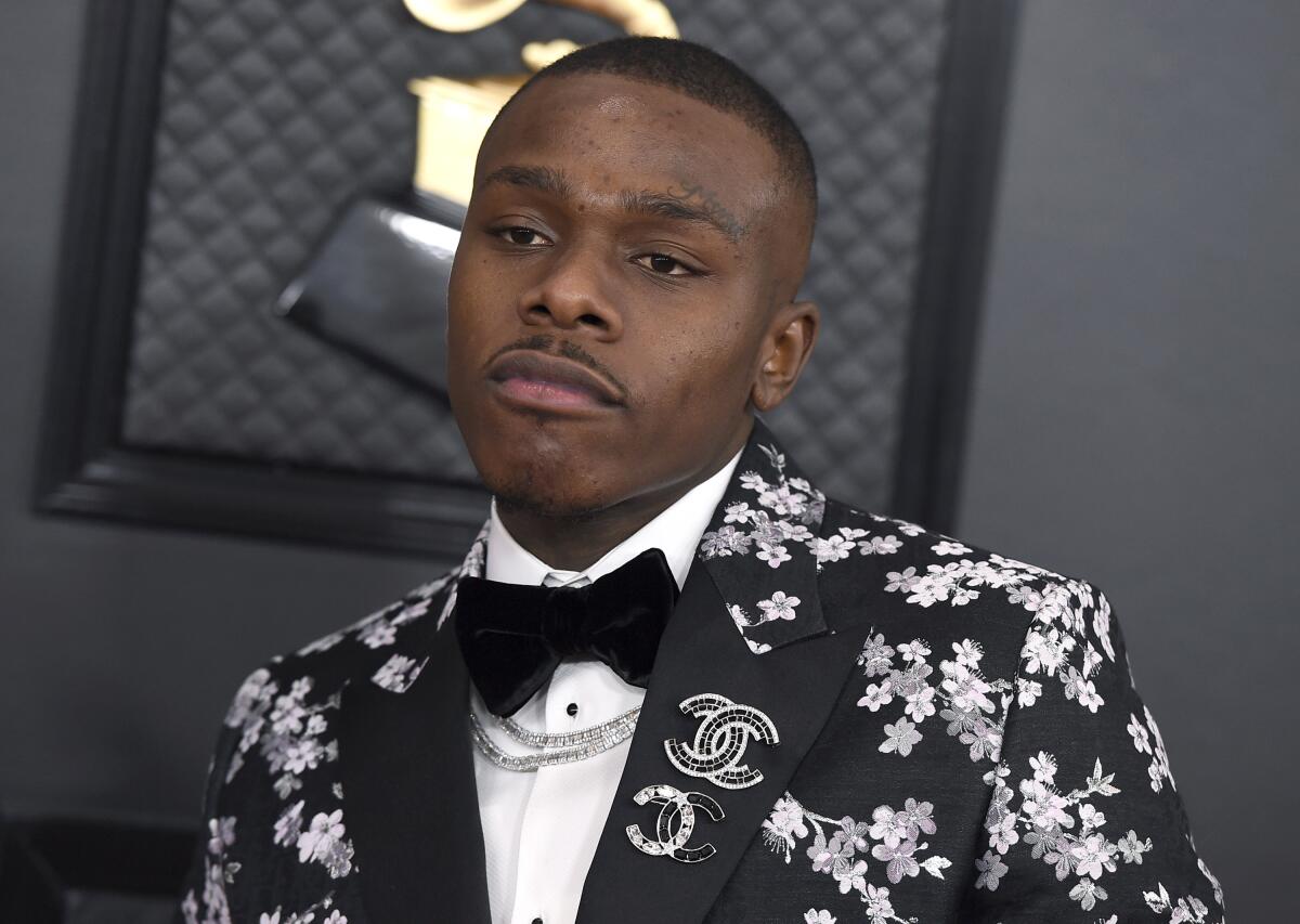 A man posing in a black-and-white floral suit and bow tie