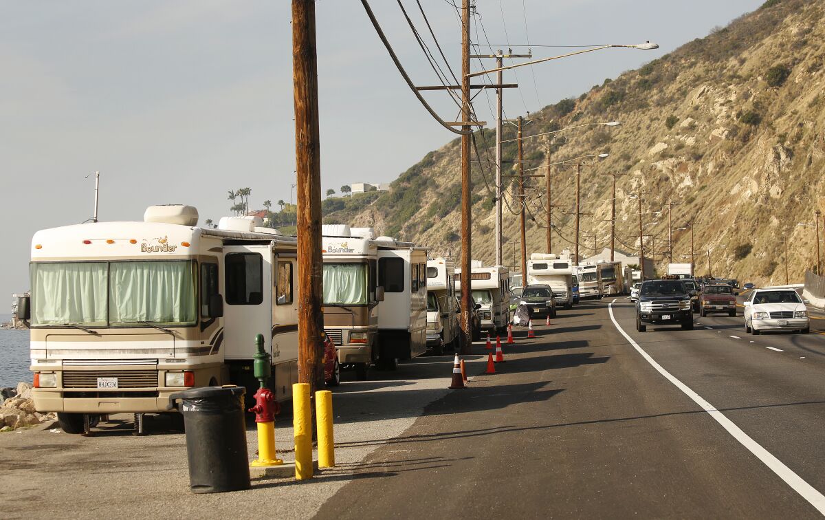 Recreational vehicles and other cars in which people are living fill the shoulder along Pacific Coast Highway at Las Tunas County Beach.