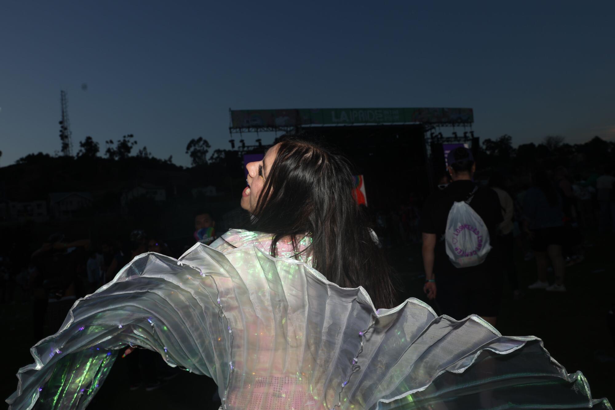 A person dances in a sparkly outfit at night during LA Pride in the Park at Los Angeles State Historic Park.
