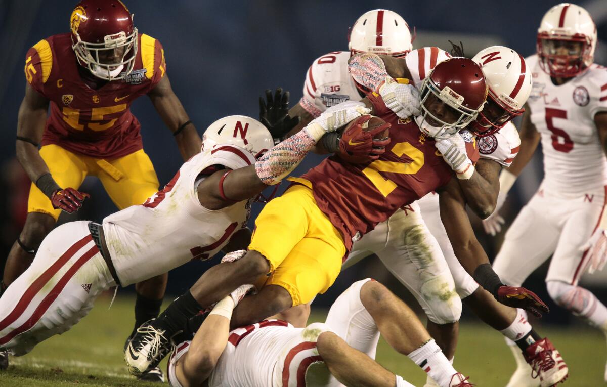 USC receiver Adoree' Jackson is hauled down by Nebraska defenders after a reception in the Holiday Bowl.