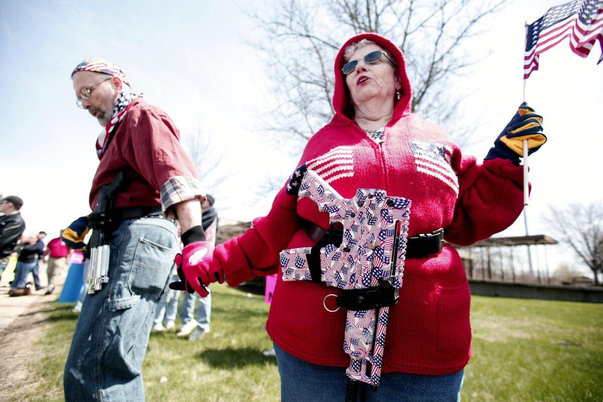 A Michigan couple carry decorated pistols at a rally for supporters of the state's open carry law last month in Romulus, Mich.