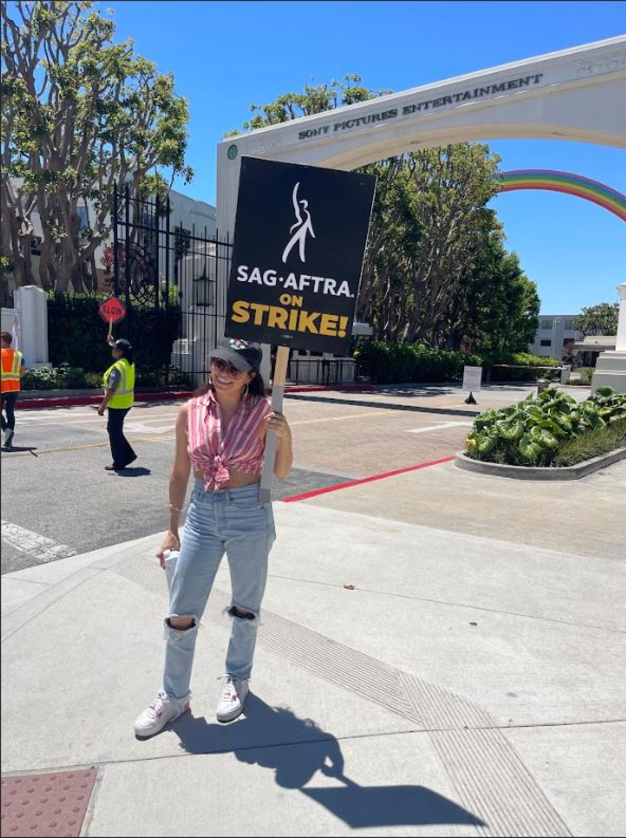 A woman holds a picket sign on a sidewalk