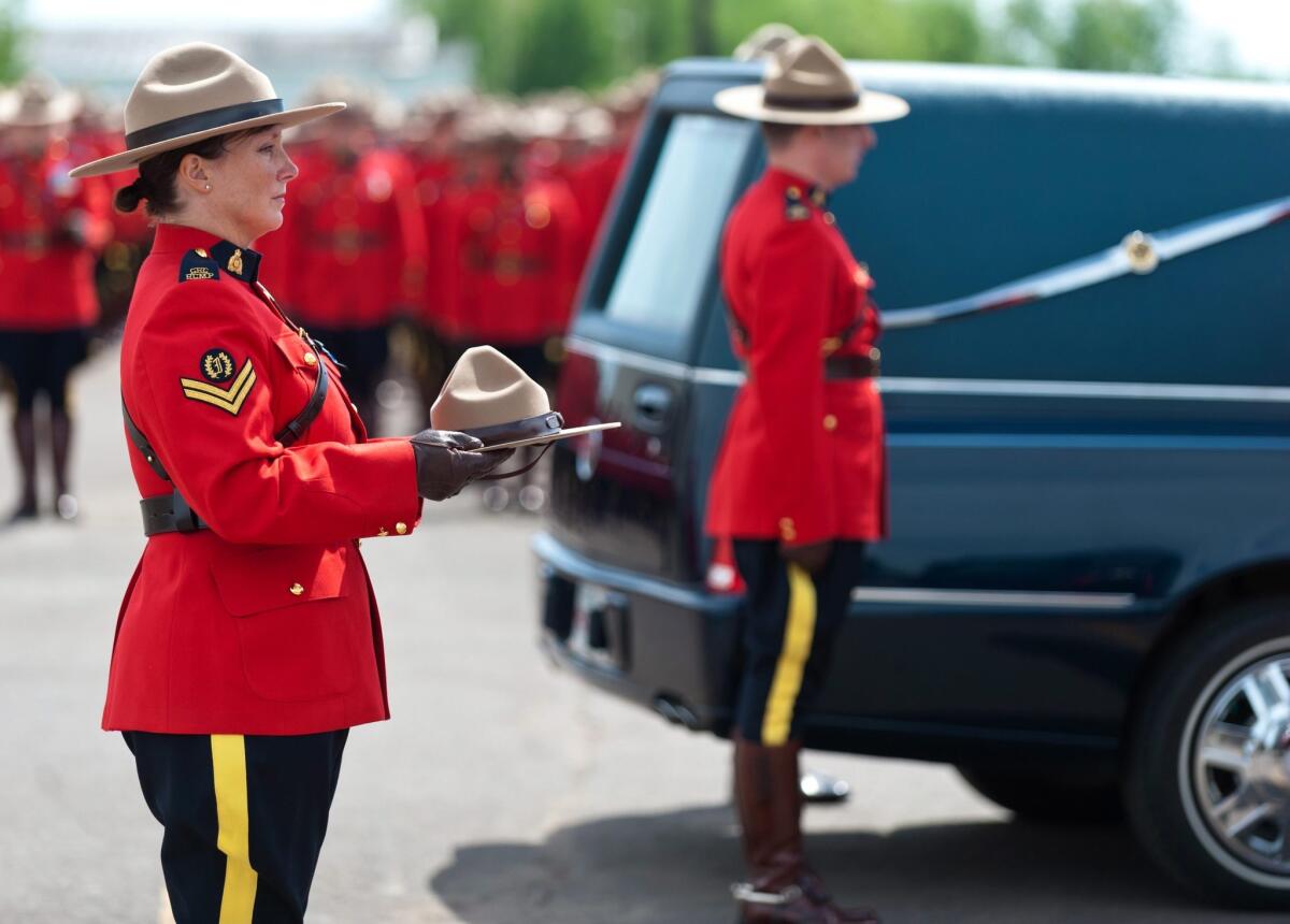 A Royal Canadian Mounted Police officer carries the hat of Constable Douglas Larche, one of three mounties killed last week during a gunman's rampage in Moncton.
