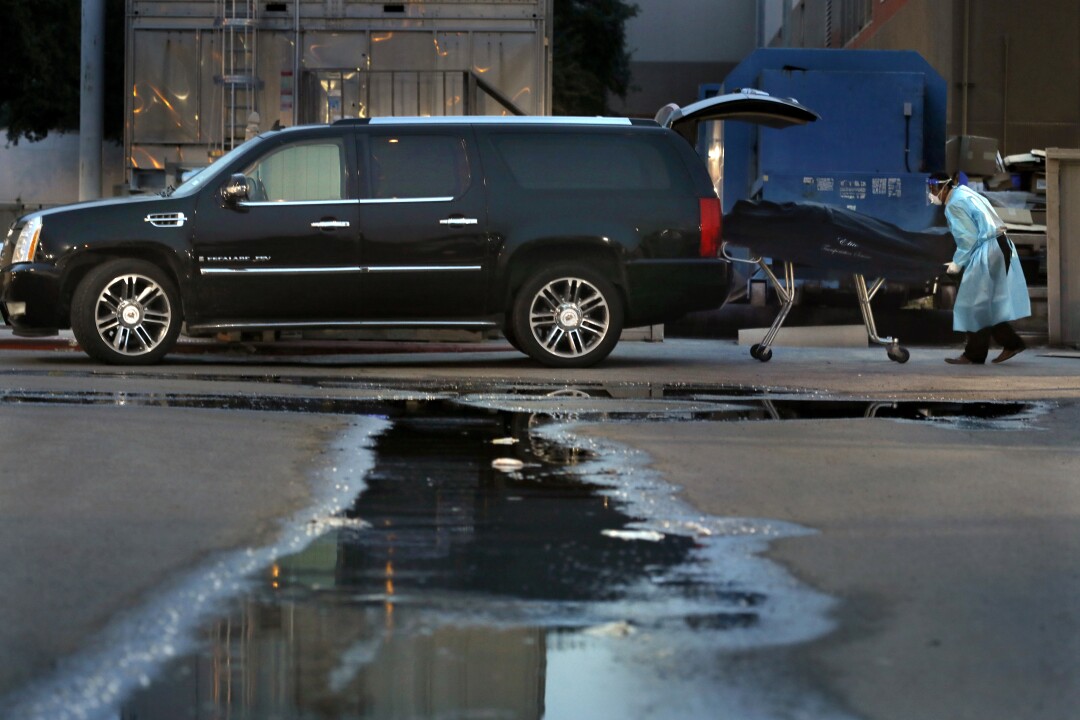 Juan Lopez loads a body into the Cadillac Escalade he uses for his Elite Transport business.