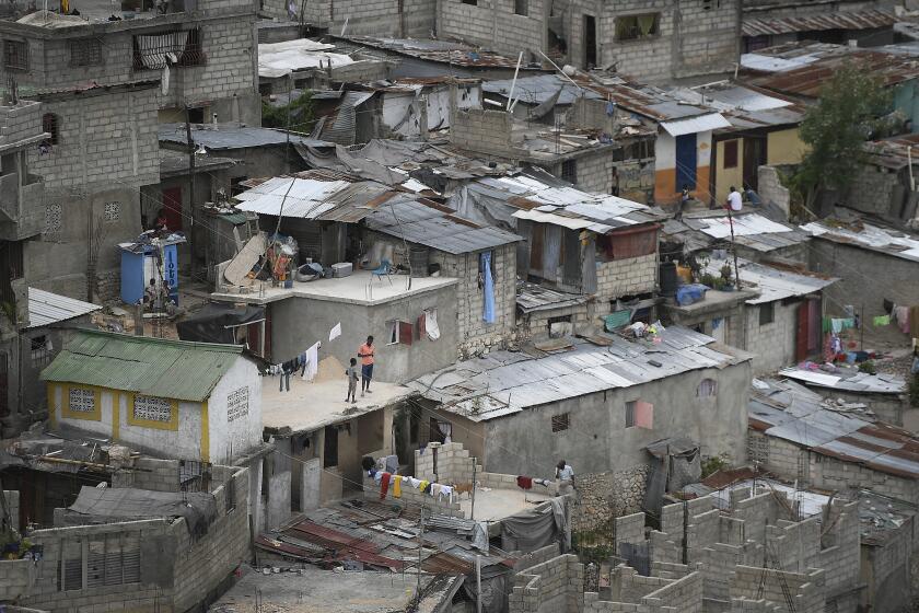 Neighbors stand on a roof in Port-au-Prince, Haiti, Monday, July 12, 2021. (AP Photo/Matias Delacroix)