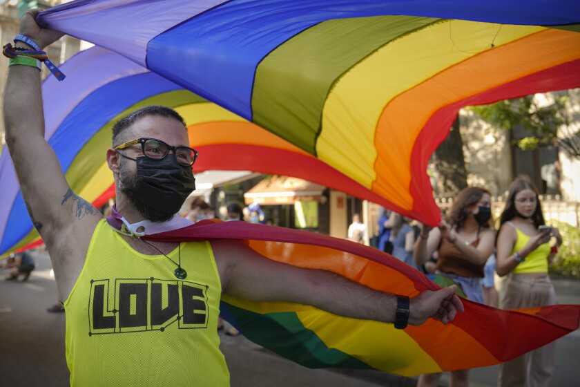 A participant waves the rainbow flag during the gay pride march in Bucharest, Romania, Saturday, Aug. 14, 2021. Several thousand LGBT supporters took to the streets in the Romanian capital of Bucharest Saturday for a gay pride parade which resumed after a year's pause due to the pandemic. (AP Photo/Vadim Ghirda)
