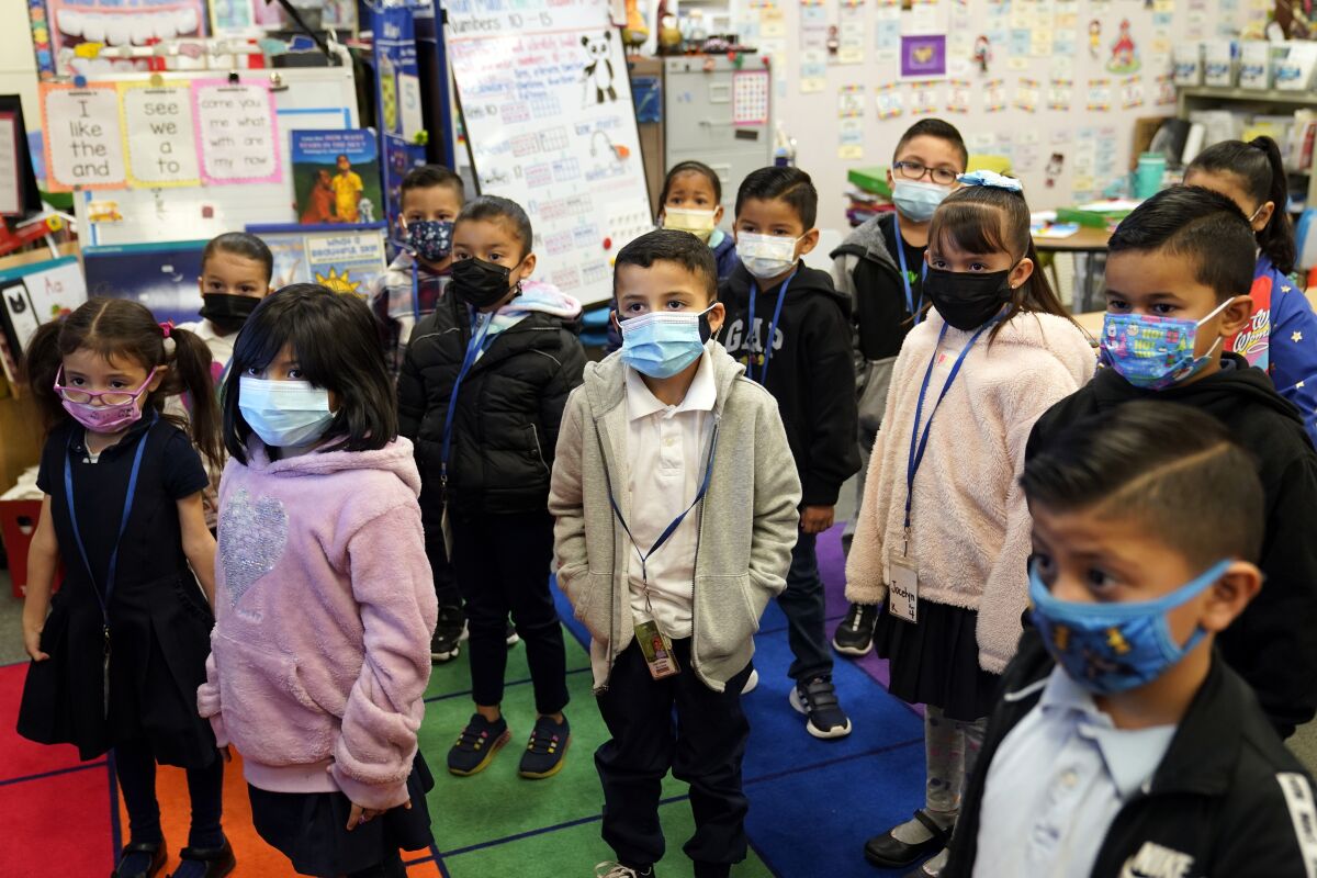 FILE - Kindergarteners wear masks while listening to their teacher amid the COVID-19 pandemic at Washington Elementary School on Jan. 12, 2022, in Lynwood, Calif. Gov. Gavin Newsom delayed a closely watched decision on lifting California's school mask mandate Monday, Feb. 14 even as other Democratic governors around the country have dropped them in recent weeks. (AP Photo/Marcio Jose Sanchez, File)